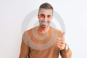 Young handsome elegant man wearing winter sweater over isolated background doing happy thumbs up gesture with hand