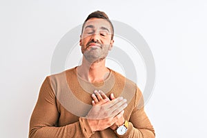 Young handsome elegant man wearing winter sweater over isolated background smiling with hands on chest with closed eyes and