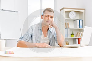 Young handsome employee sitting at the desk