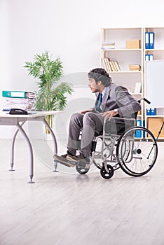 The young handsome employee in wheelchair at the office