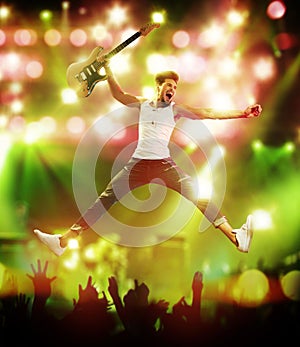 Young, handsome guitarist jumping on the stage