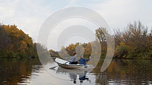 Young handsome guy and a beautiful girl takes a photo in a boat on a lake in a fairy autumn forest