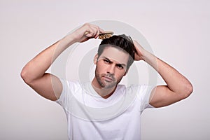 A young handsome guy combs a wooden comb