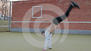 A young, handsome guy does a back flip. Parkour in town.