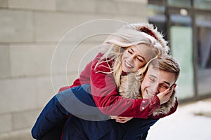 Young handsome guy giving girlfirend piggyback ride