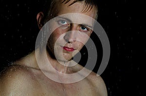 Young handsome guy in shower. Water, cleanliness and freshness