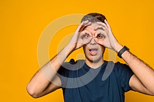 Young handsome guy shows gesture binocle isolated