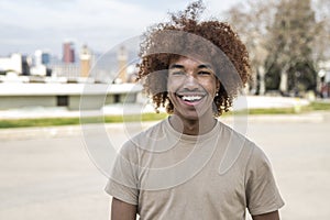 Young handsome guy smiling relaxed and looking at camera in the street. Confident happy man laughing and staring at