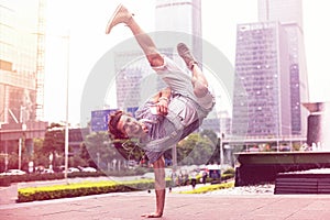 Young handsome guy is standing on the hand on the background of the urban landscape. Stylish dancer on city background.