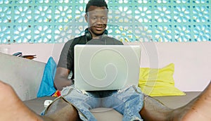 Young handsome and happy hipster black African American business man working with laptop computer and headphones smiling satisfied