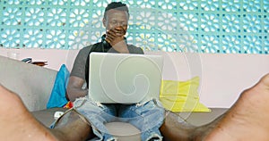 Young handsome and happy hipster black afro American business man working with laptop computer and headphones smiling satisfied