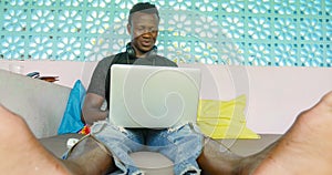 Young handsome and happy hipster black afro American business man working with laptop computer and headphones smiling satisfied