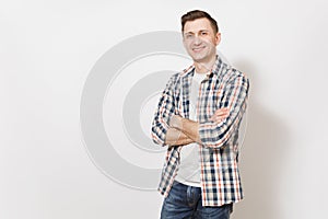 Young handsome happy smiling man in gray t-shirt, blue jeans, checkered shirt holding hands crossed over chest