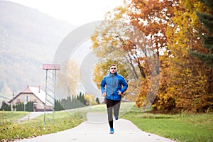 Young handsome hipster athlete running against colorful autumn n