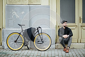 Young handsome hipster man sitting and posing and bicycle on the street