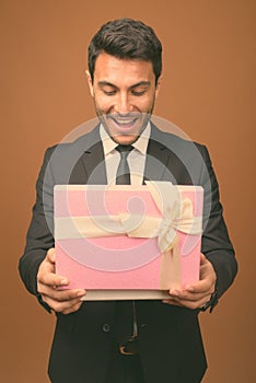 Young handsome Hispanic businessman against brown background