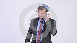 Young handsome Hispanic businessman listening to music