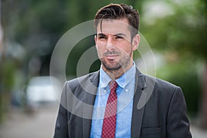 Young handsome Hispanic businessman wearing suit while thinking outdoors