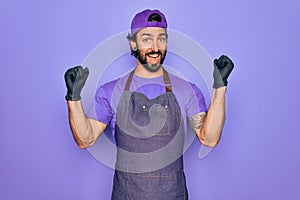 Young handsome hispanic man with bear wearing professional apron working as tattoo artist celebrating surprised and amazed for
