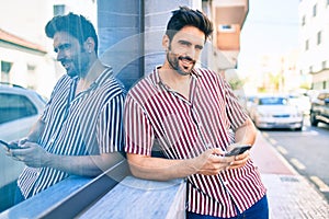 Young handsome hispanic man with beard smiling happy outdoors using smartphone
