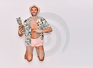 Young handsome hispanic man on vacation wearing swimwear, floral shirt and hat smiling happy