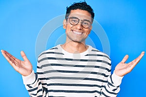 Young handsome hispanic man wearing casual sweater and glasses celebrating victory with happy smile and winner expression with