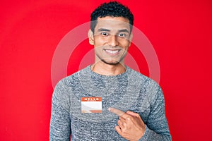 Young handsome hispanic man wearing hello my name is sticker identification smiling happy pointing with hand and finger