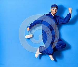 Young handsome hispanic man wearing painter uniform and cap smiling happy