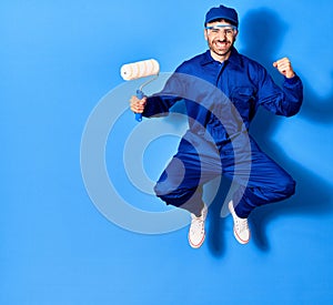 Young handsome hispanic man wearing painter uniform and cap smiling happy