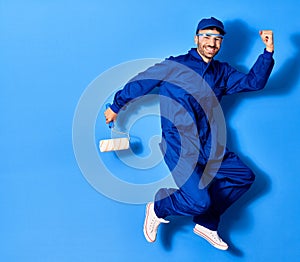 Young handsome hispanic man wearing painter uniform and cap smiling happy