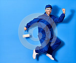 Young handsome hispanic man wearing painter uniform and cap smiling happy