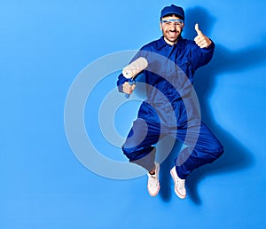 Young handsome hispanic man wearing painter uniform and glasses smiling happy