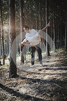 Young handsome Indian couple dancing in forest wearing white