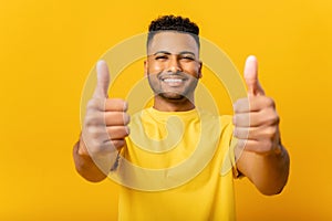 Young handsome Indian guy showing thumbs up isolated on yellow
