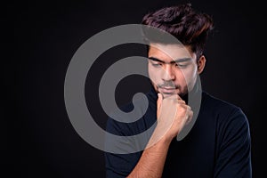 Young handsome Indian man against black background