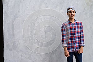 Young handsome Indian man against concrete wall in the streets o