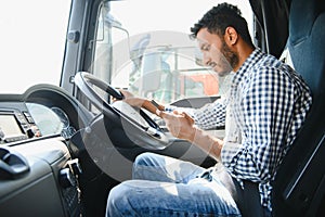 Young handsome indian man using smart phone in his truck.