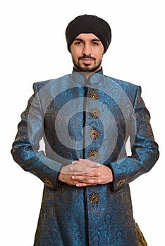 Young handsome Indian Sikh intertwining fingers together wearing