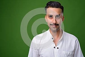 Young handsome Iranian man with mustache against green backgroun photo