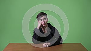 Young handsome Iranian teenage boy against green background