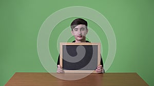 Young handsome Iranian teenage boy against green background