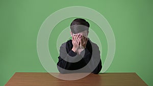 Young handsome Iranian teenage boy against green background