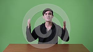 Young handsome Iranian teenage boy against green background