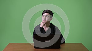 Young handsome Iranian teenage boy against green background