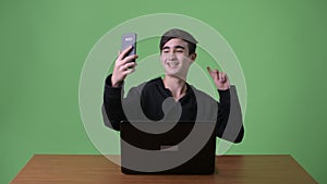 Young handsome Iranian teenage boy against green background