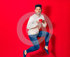 Young handsome latin man smiling happy drinking cup of coffee