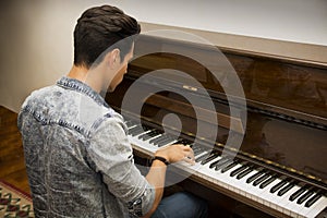 Young handsome male artist playing classical upright piano