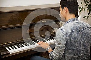 Young handsome male artist playing classical upright piano