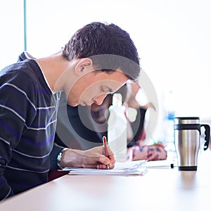 Young, handsome male college student sitting in a classroom full