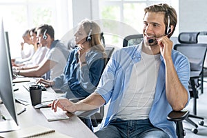 Young handsome male customer support phone operator with headset working in call center